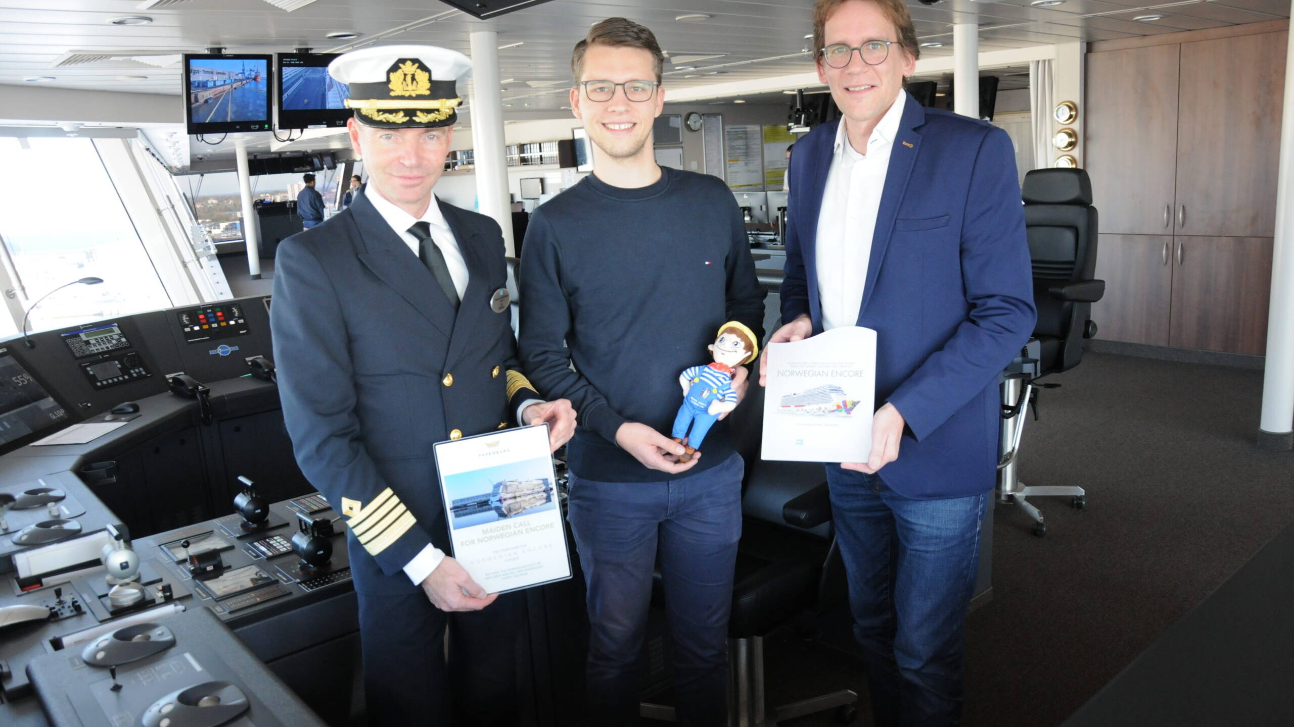Plakettentausch auf der Brücke der Norwegian Encore: Kapitän Niklas Persson (links) freute sich über das Präsent von Werftsprecher Florian Feimann und PMG-Chef Kai Nehe (von links). Foto: Christoph Assies